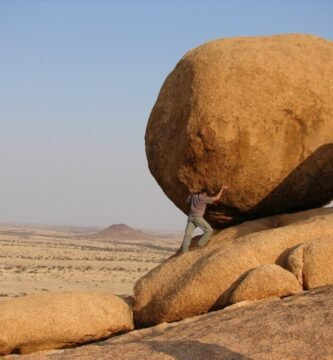 man representing sisyphus standing beside rock formation