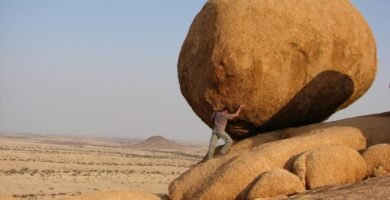 man representing sisyphus standing beside rock formation